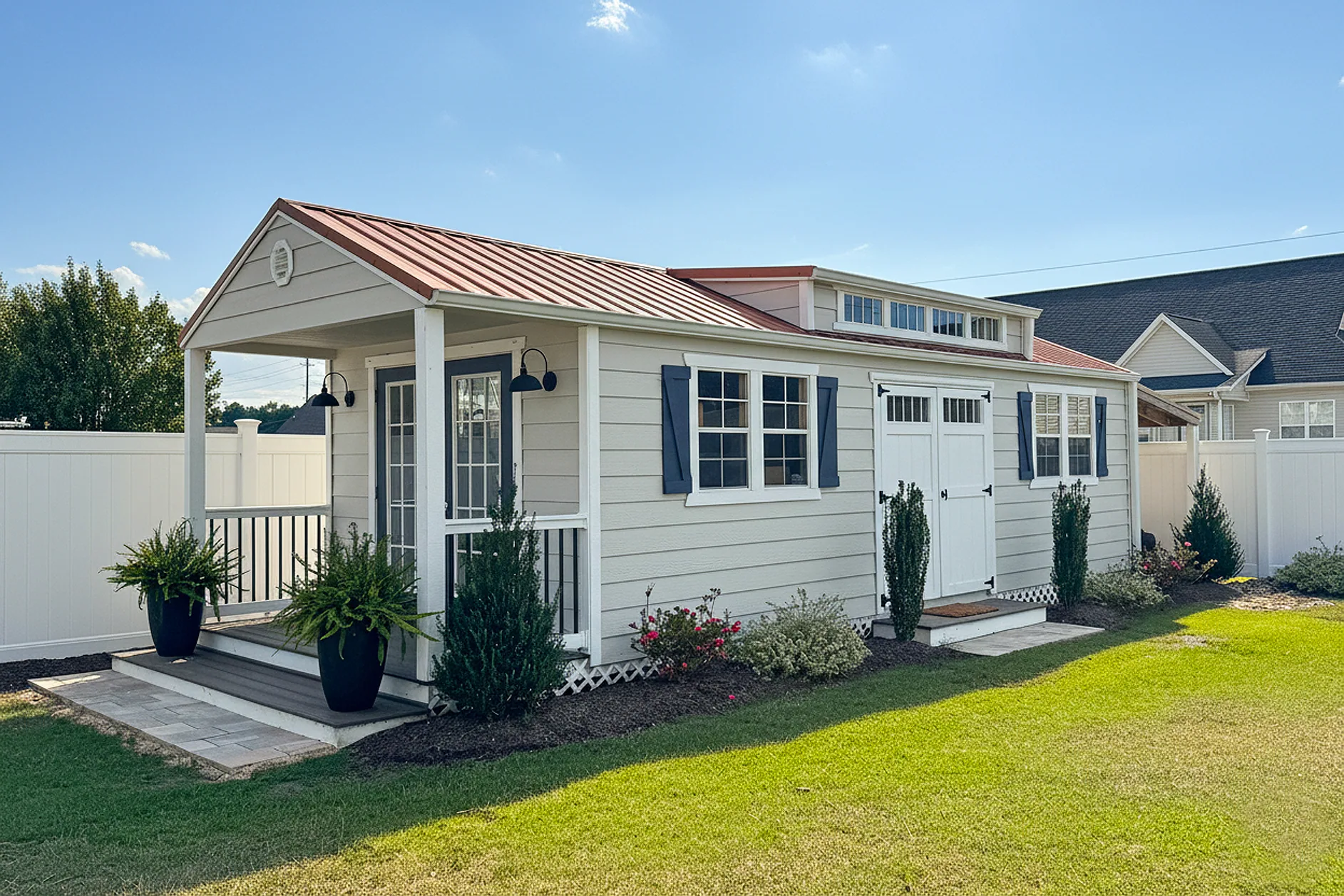Tiny home with a covered porch, dormer and metal roof in a backyard